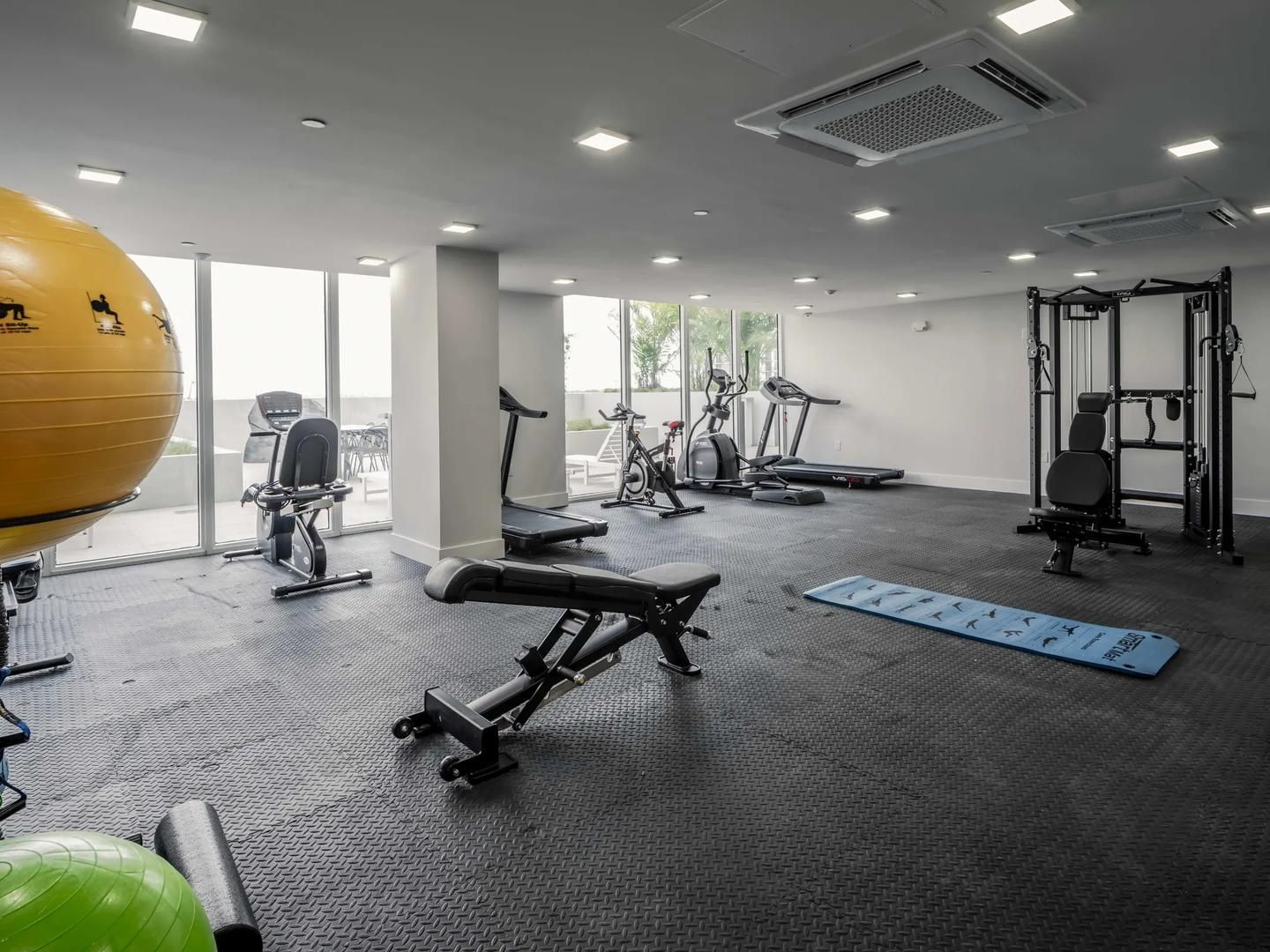 A gym with exercise equipment, a yoga mat, and a large exercise ball.