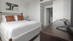 Een hotelkamer met een bed, nachtkastje, lamp en een grote spiegel.