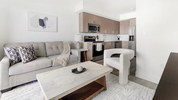 Ein modernes Wohnzimmer mit einer Couch, einem Couchtisch und einer Küchenzeile mit Geräte.