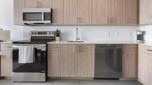 Una cocina moderna equipada con microondas, estufa, horno, pileta y lavavajillas.