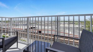 Ein Balkon mit Blick auf einen Bahnhof und die umliegenden Gebäude.