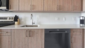 Eine moderne Küche mit Holzschränken, einer Edelstahlspüle, einem Geschirrspüler und einer Kaffeemaschine.