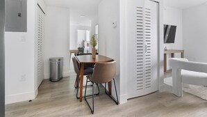 Ein modernes Interieur mit Essbereich, einem weißen Schrank mit Klappläden und einem an der Wand befestigten Fernseher.