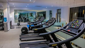 Un gimnasio con cintas de correr, máquinas de pesas y un espejo grande.