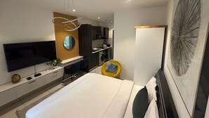 Una habitación de hotel moderna con cama, televisión, escritorio y baño.