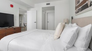Ein Hotelzimmer mit Bett, Fernseher, Schreibtisch und Stuhl.