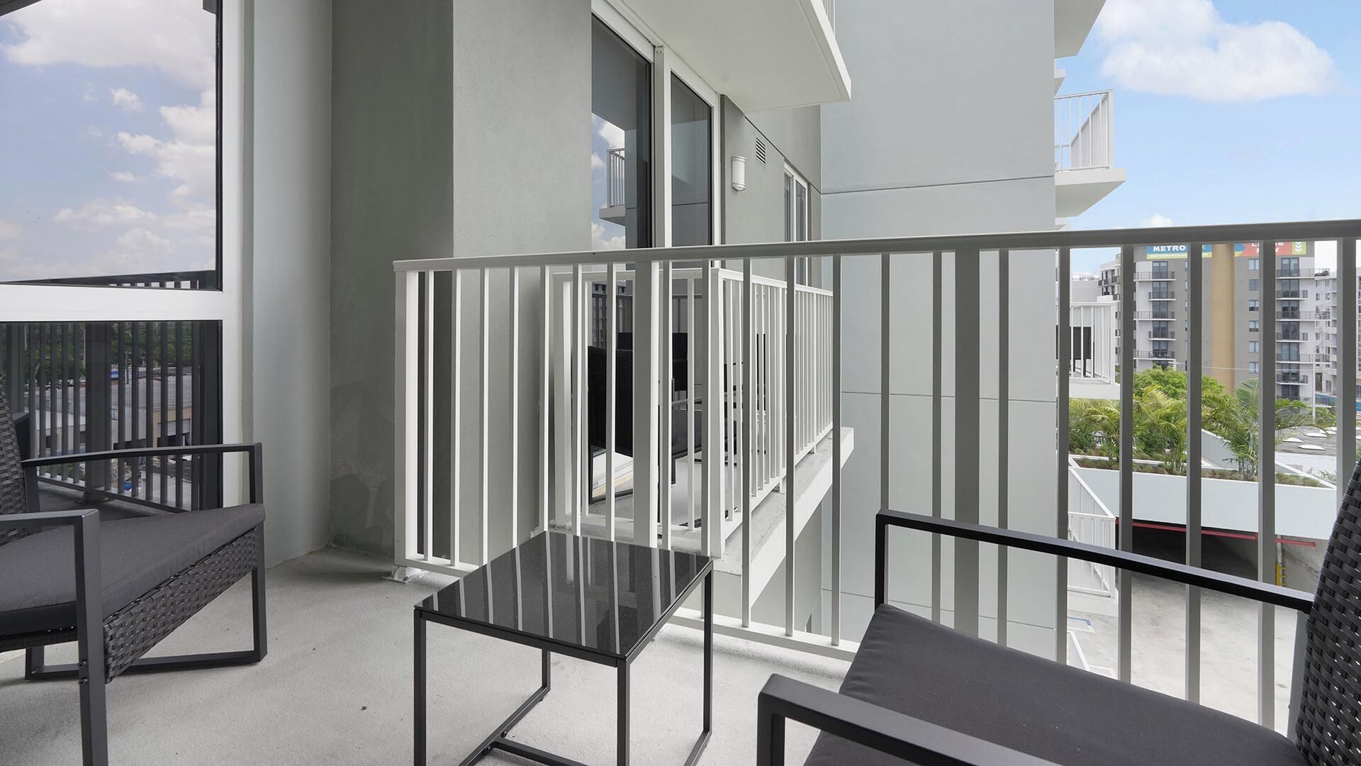 Een balkon met een glazen tafel, een bank en een leuning.