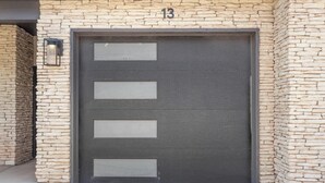 Eine Garagentür mit steinverkleideter Fassade und der Zahl 13 darüber.