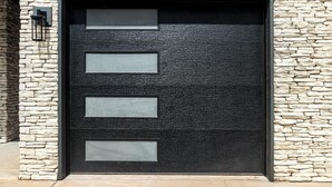 Une porte moderne avec une façade en pierre et trois panneaux de verre rectangulaires.