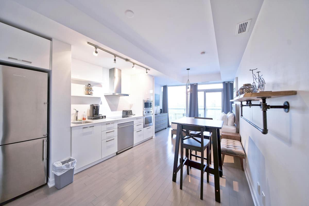 A modern kitchen with white cabinetry, a dining area with a table and chairs, and a built-in bench.