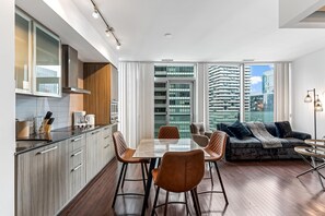Une cuisine moderne avec un coin repas, un canapé et une vue sur de hauts immeubles.