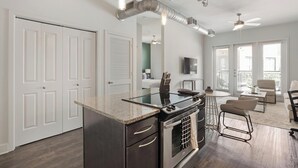 Une cuisine moderne avec un îlot central, un coin repas doté de tabourets de bar et un salon avec un canapé et des fauteuils.