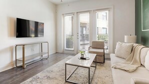 Un salon moderne avec un téléviseur à écran plat, une table basse, un canapé et un fauteuil.