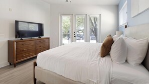 A bedroom with a bed, a TV on a wooden dresser, and a view of the outside through a door. - Landing | Spectacular Studio, Pool, Clubhouse (Dallas)