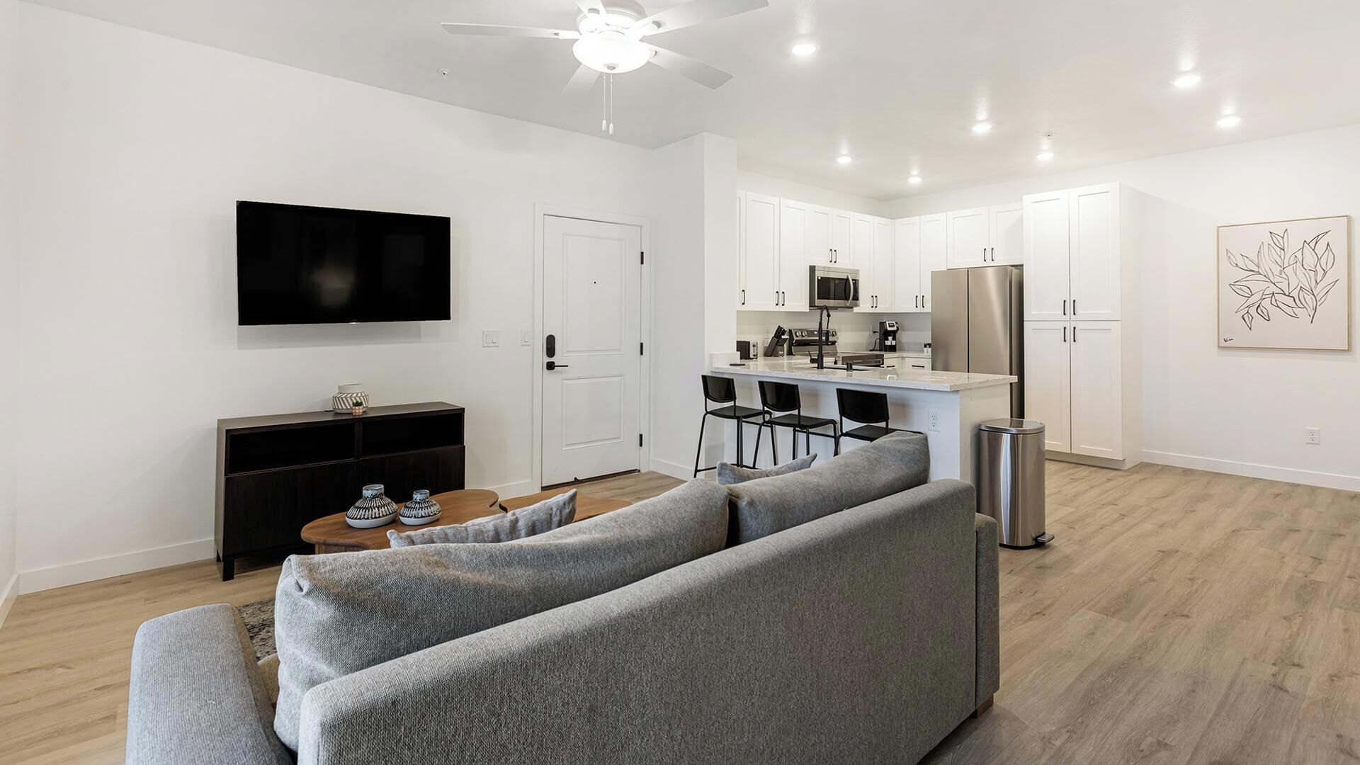 Un salon moderne avec un canapé gris, un téléviseur à écran plat et une petite table basse.
