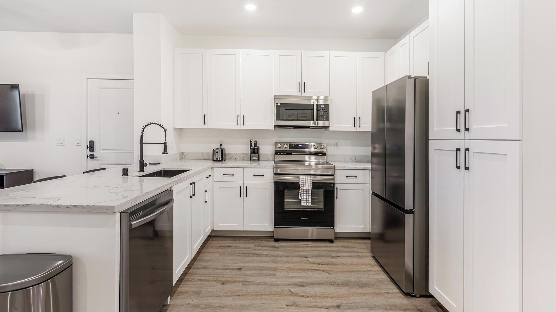 Una cocina moderna con armarios blancos, electrodomésticos de acero inoxidable y encimera de mármol.
