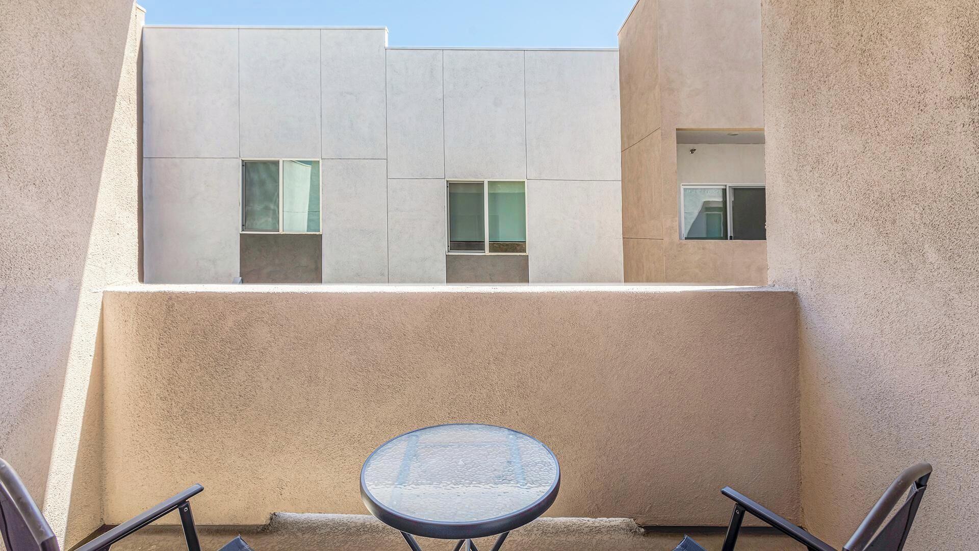 Il s’agit d’un bâtiment moderne, doté d’une façade plate et de fenêtres rectangulaires. On y trouve, à l’avant, une table ronde accompagnée de deux chaises.