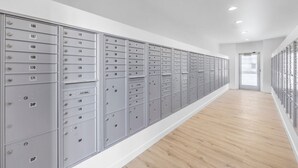 A long hallway with metal lockers on both sides, wooden flooring, and a door at the end. - Landing | Amazing 1BD, Gym, Clubhouse (North Las Vegas)