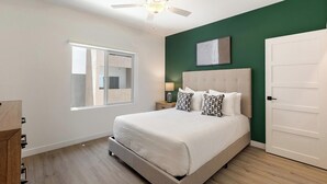 A bedroom with a bed, a nightstand, a lamp, a ceiling fan, a window, and a door. - Landing | Amazing 1BD, Gym, Clubhouse (North Las Vegas)