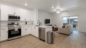 A modern kitchen with white cabinets, stainless steel appliances, and a wooden floor. - Landing | Amazing 1BD, Gym, Clubhouse (North Las Vegas)