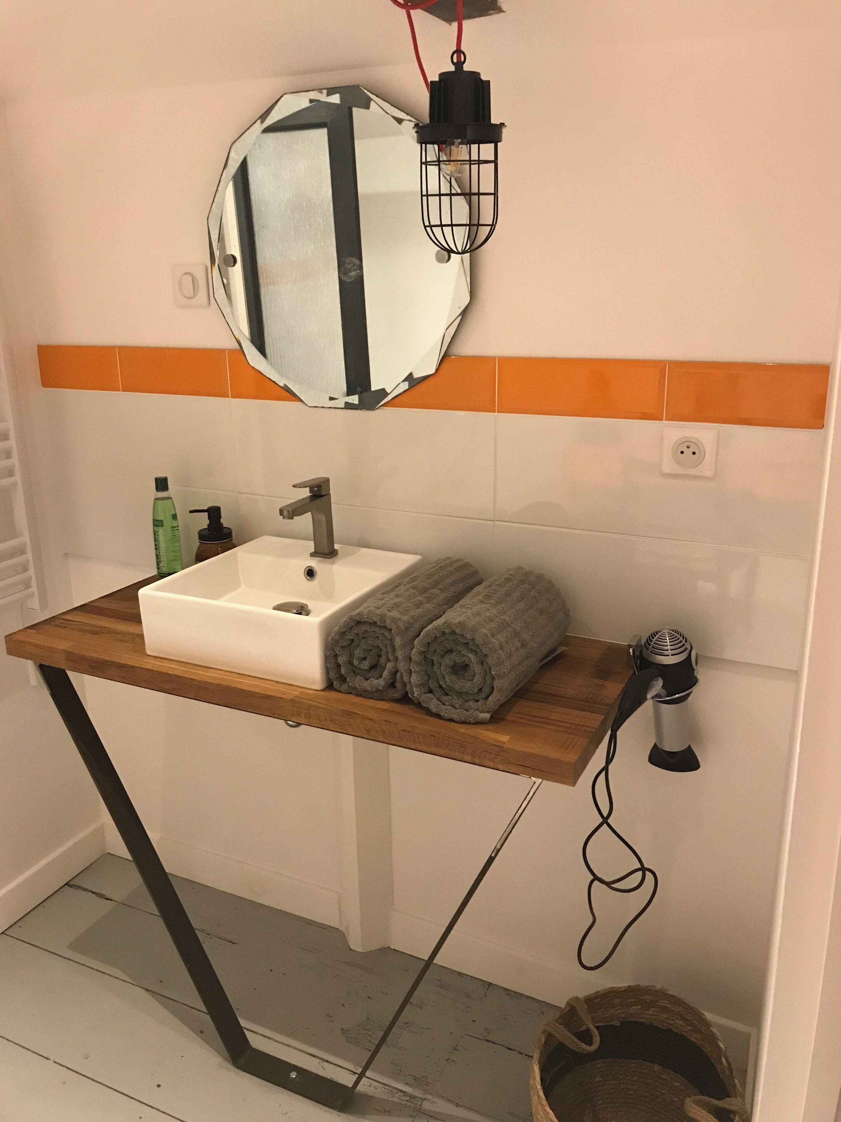 Une salle de bain avec un meuble-lavabo en bois, un lavabo blanc, un miroir et un porte-serviettes.