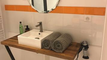 Une salle de bain avec un meuble-lavabo en bois, un lavabo blanc, un miroir et un porte-serviettes.