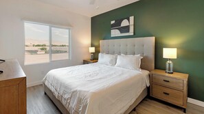 A bedroom with a large bed, two bedside tables, a window, and a green wall. - Landing | Beautiful 2BD, Clubhouse, Pool (North Las Vegas)