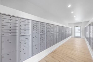 A long hallway with metal lockers on both sides, wooden flooring, and a door at the end. - Landing | Amazing 2BD, Pool, Gym (North Las Vegas)