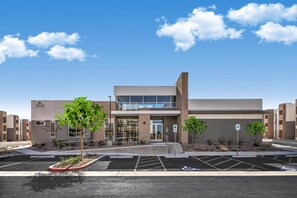 A modern building with a flat roof, large windows, and a parking lot with marked handicapped spaces. - Landing | Amazing 2BD, Pool, Gym (North Las Vegas)
