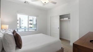 Un dormitorio con cama, ventana, ventilador de techo y armario.