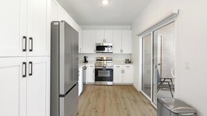 Een moderne keuken met witte kastjes, roestvrijstalen apparatuur en een houten vloer.