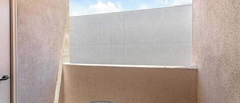 A small, enclosed balcony with a view of the sky and a door to the left.