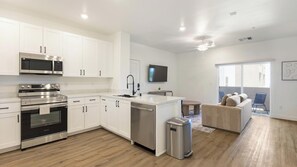 A modern kitchen with white cabinets, stainless steel appliances, and a central island. - Landing | Amazing 1BD, Pool, Gym (North Las Vegas)