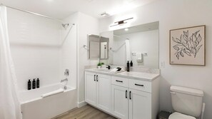 Uma casa de banho moderna com chuveiro, lavatório com espelho e sanita.