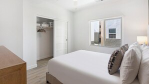 Ein Schlafzimmer mit Bett, Kleiderschrank, Fenster und Nachttisch.
