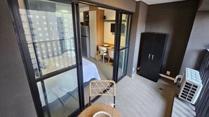 Um apartamento moderno com varanda, área de jantar e cozinha visível através de portas de vidro.