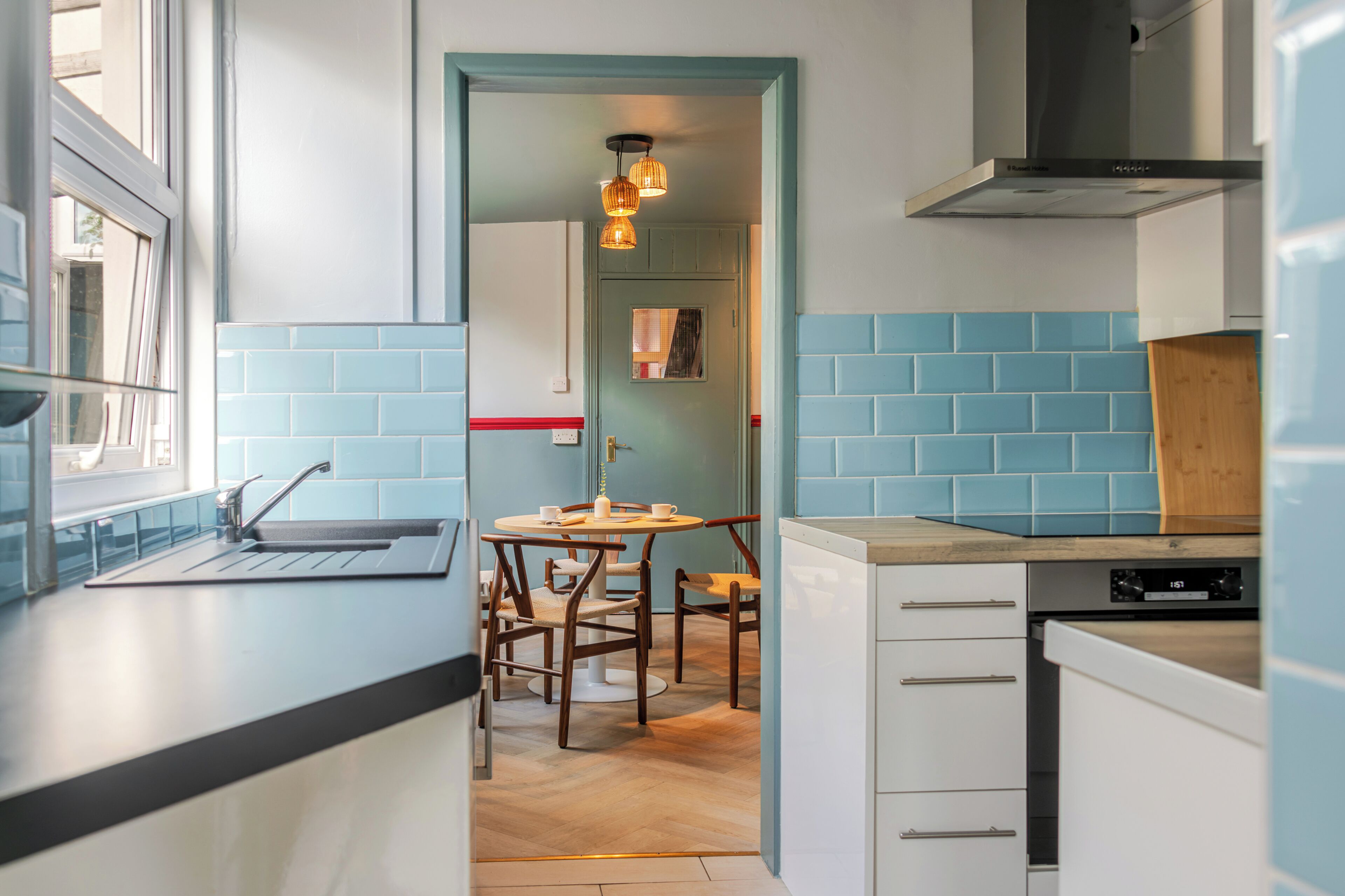 A modern kitchen with a dining area, a window, and a view of the street.