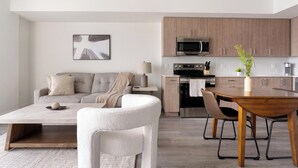 Una sala de estar moderna con sofá, una mesa de centro y una zona de comedor con una mesa de madera y sillas.