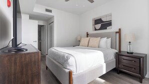 A bedroom with a bed, bedside table, lamp, and a TV on a stand. - Landing | Stylish 1BD, Gym (Hialeah)