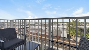 A balcony with a view of railway tracks and buildings.
