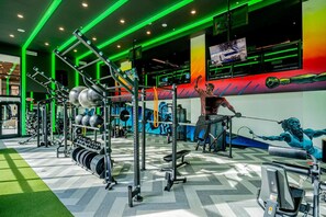 A gym with exercise equipment, a TV screen, and a mural on the wall.