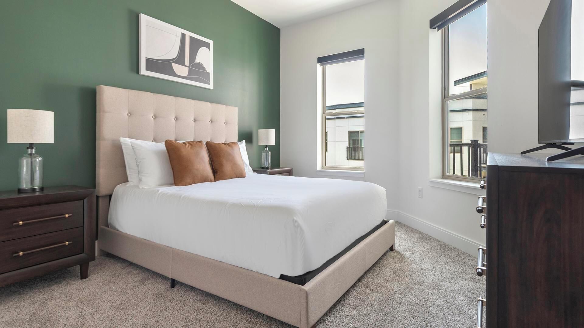 A bedroom with a large bed, two bedside tables, a dresser, and a window with a view.