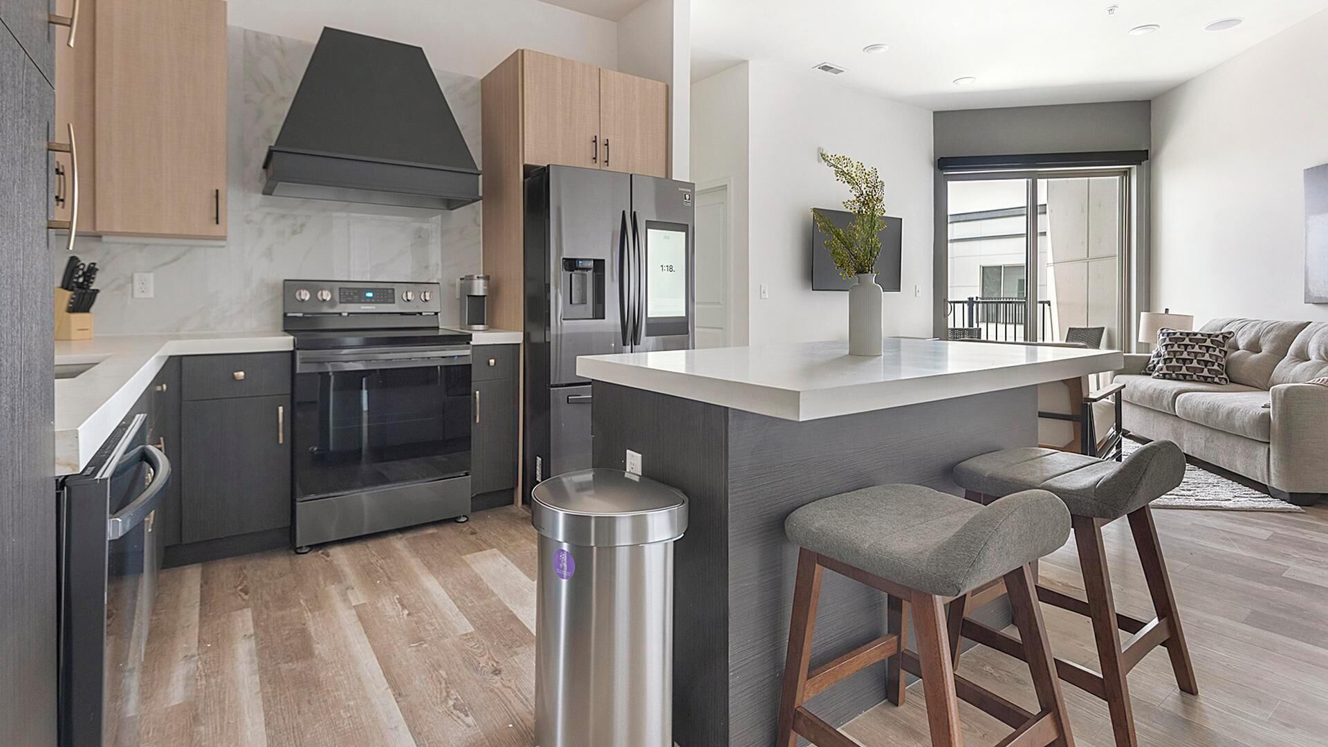A modern kitchen with a central island, stainless steel appliances, and a grey color scheme.