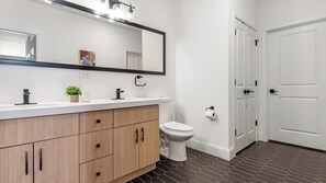 A modern bathroom with a wooden vanity, a toilet, and a white door. - Landing | Incredible 1BD, Gym, Yoga Studio (St. Louis)