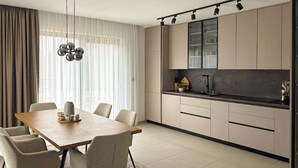Una cucina moderna con zona pranzo, che include un tavolo e sedie in legno, una lampada a sospensione e un'isola con lavello.