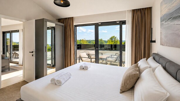 Una camera d'albergo con un letto grande, vista all'esterno e un balcone con posti a sedere.