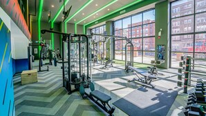 Ein Fitnessstudio mit unterschiedlichen Trainingsgeräten, großen Fenstern und einem Zickzack-Boden.