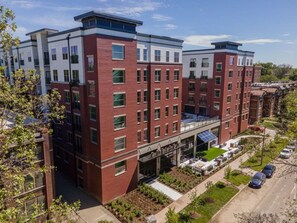 A multi-story building with a flat roof, large windows, and a covered outdoor seating area. - Landing | Stunning 1BD, Gym, Yoga Studio (St. Louis)