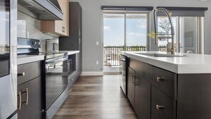 A modern kitchen with a central island, built-in oven, and a view to a balcony. - Landing | Stunning 1BD, Gym, Yoga Studio (St. Louis)