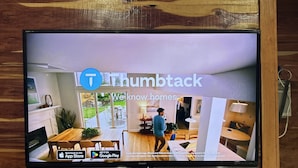 A television displaying a home interior with a dining area, kitchen, and living space. - Whoa-Man Ultra Cozy Aggieland  Cabin (North Zulch)